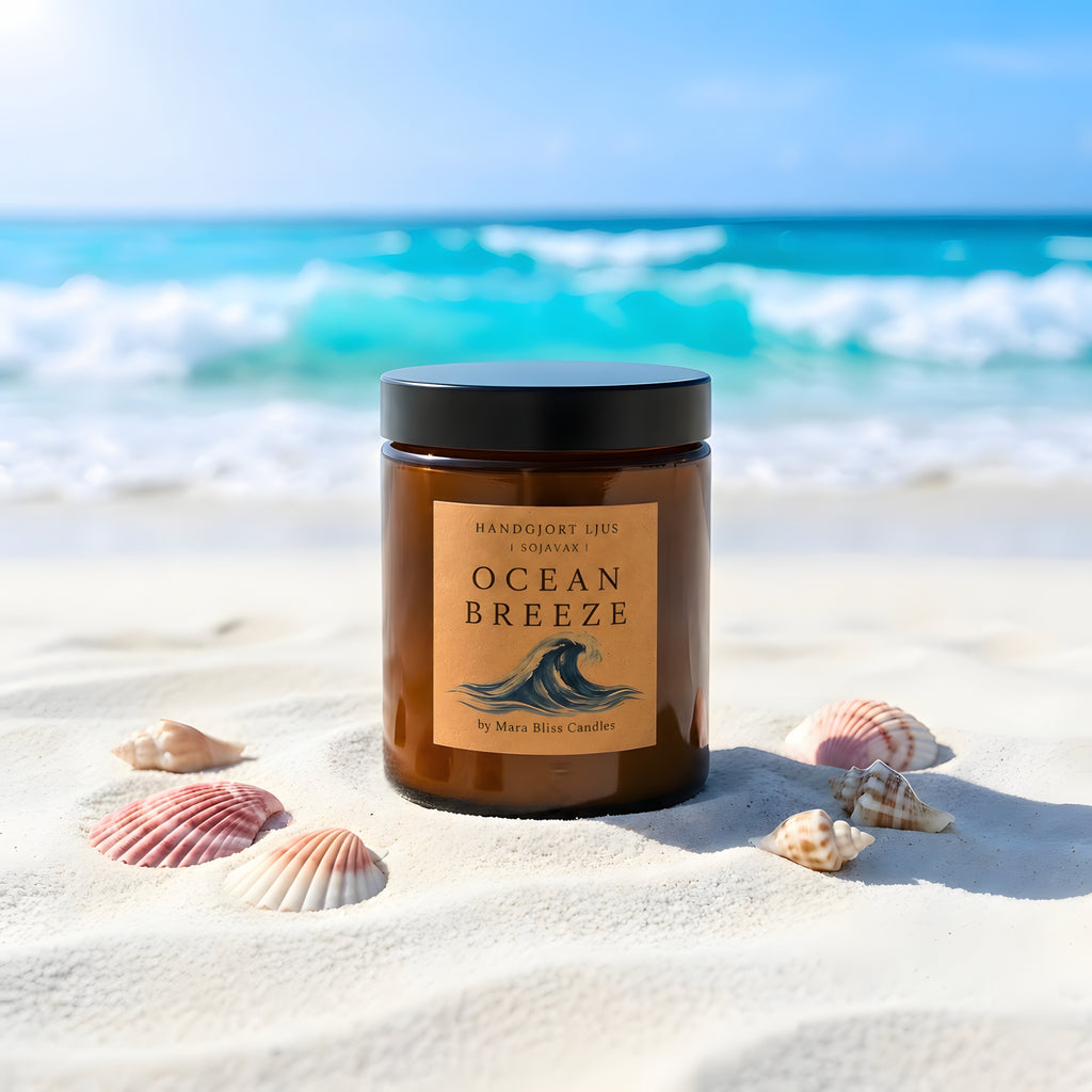 Candle labeled 'Ocean Breeze' on a sandy beach with shells and ocean in the background
